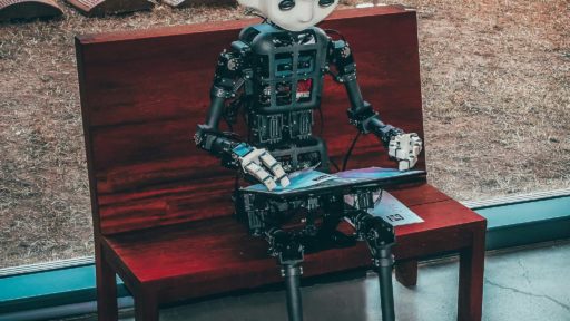 Mechanical nuts and bolts robot is sat at a bench with a laptop clearly automating their social media using Quuu
